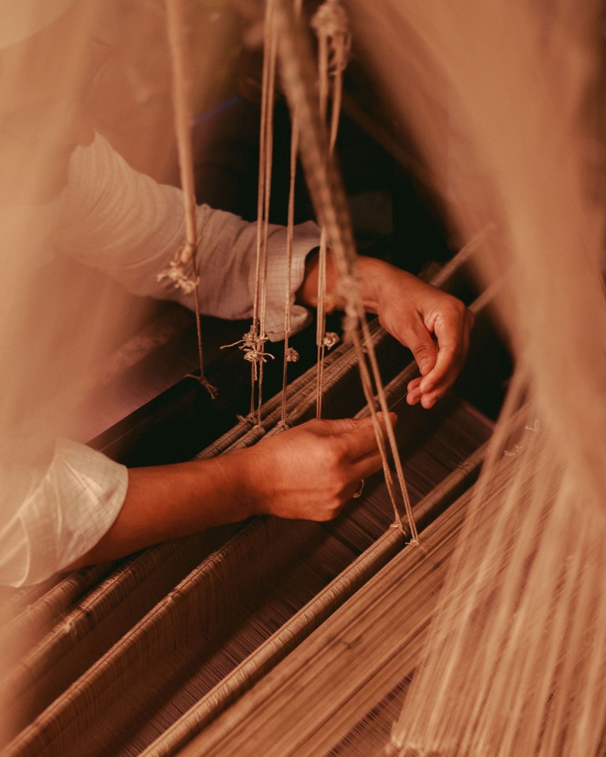 Close detail of hands threading a traditional handloom.